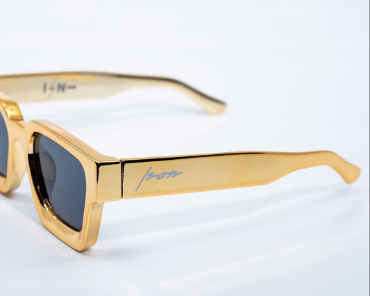Gold-framed sunglasses with dark lenses on a white background