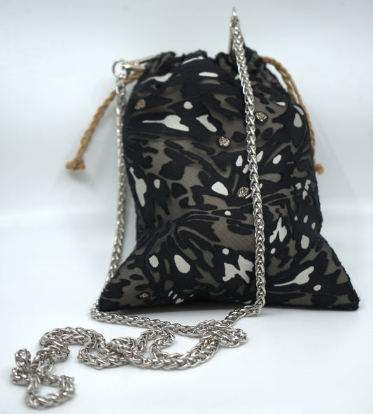Black floral patterned bag with a silver chain on a white background