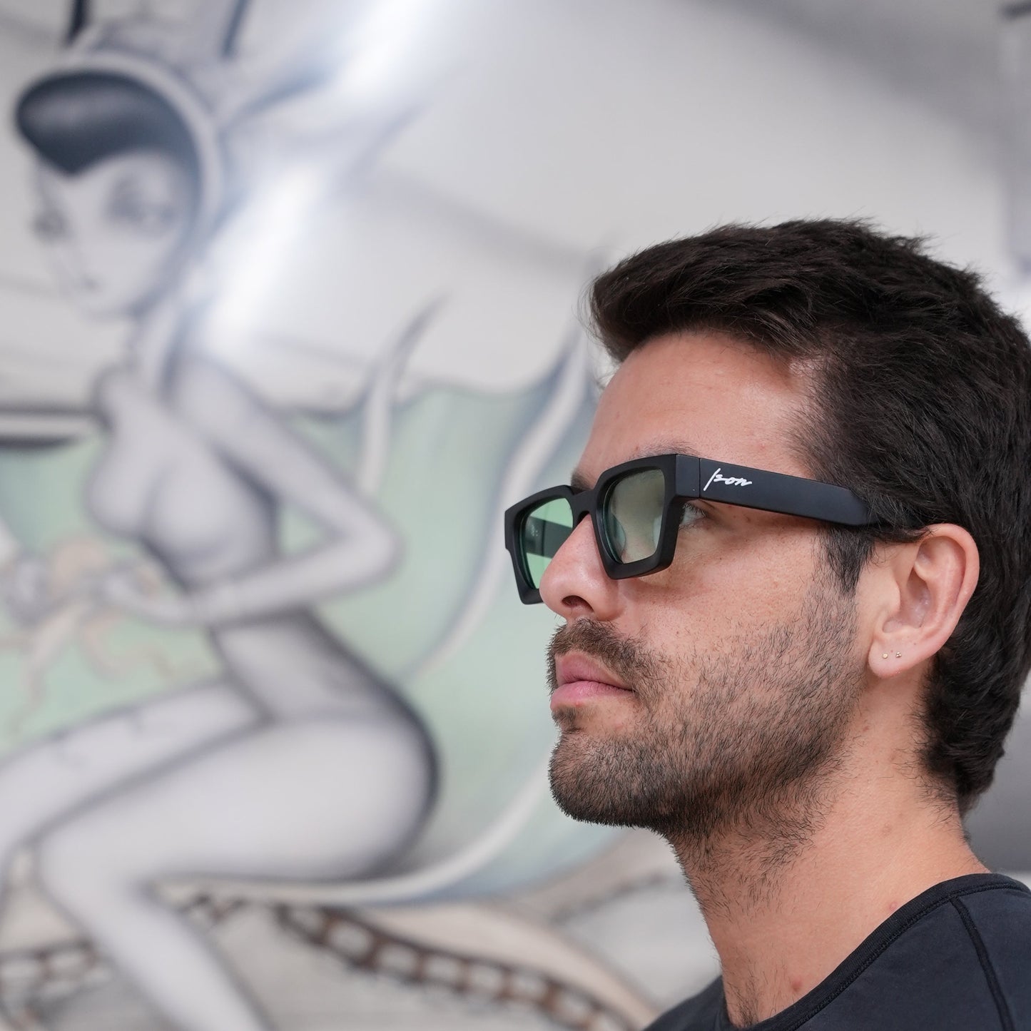 Man wearing Ison Couture Matte Mint bold square sunglasses with green lenses in front of art