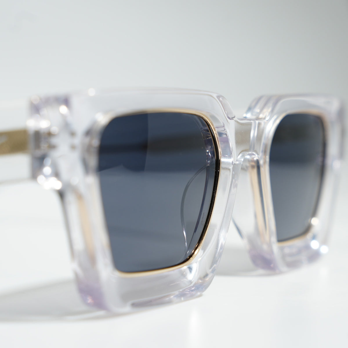 Close-up of the Crystal Clear & Gold frame front showing the gold-lined lens rim around the dark smoke polarized lens