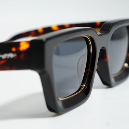 Close-up of Dark Tortoise frame showing amber tortoise flecks on the temple, Ison signature, and gold lens rim