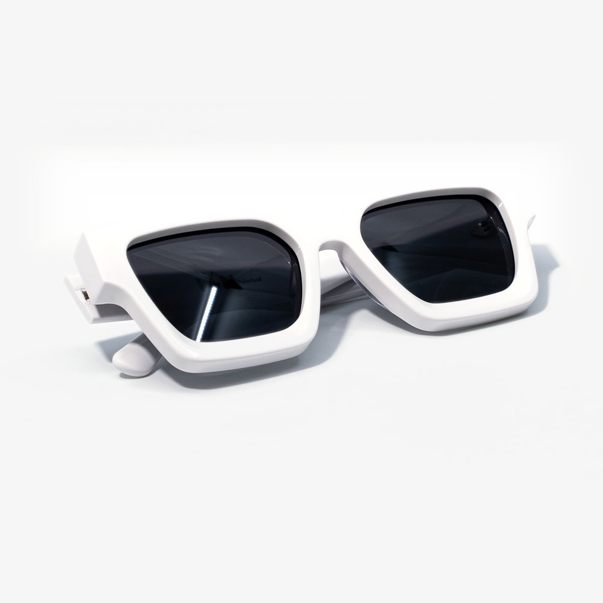 Polar White sunglasses folded, smooth white bio-acetate frame with dark smoke lenses